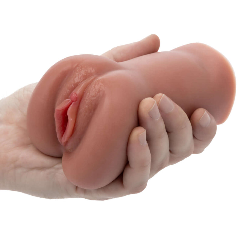 Stroke It Liquid Silicone Juicy Pussy Brown Masturbator held in hand, showcasing realistic design and texture.