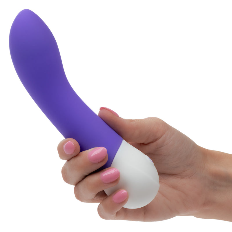 Person holding the Basic Essentials Intense Power G Vibrator Purple, showcasing its ergonomic design and vibrant color.