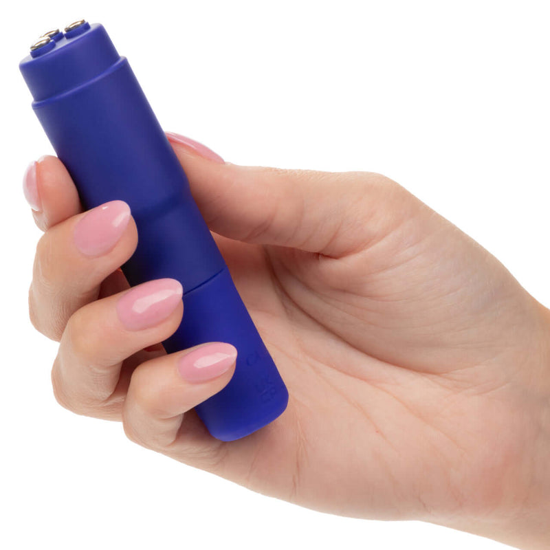 Hand holding Kyst Mega-Mite Purple rechargeable bullet vibrator with interchangeable silicone tips for customizable pleasure.
