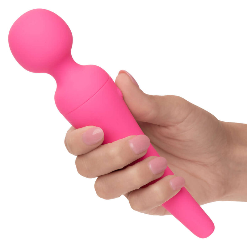Hand holding pink Couture Collection Body Wand massager made of waterproof silicone with multiple vibration speeds.