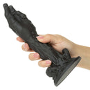 A hand holding the Monster Dong The Zombie Silicone Dildo 9 inch Black showcasing its detailed design and firm structure.
