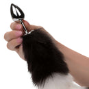 Running Wild black and white tail butt plug held in hand, featuring a metallic probe and luxurious fur tail.