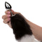 Running Wild black and white tail butt plug held in hand, featuring a metallic probe and luxurious fur tail.