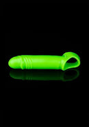Fluorescent green glow-in-the-dark penis sleeve with ball strap on black background.