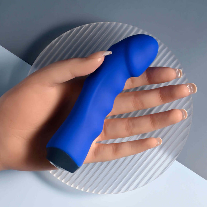 Blue Banger Petite Vibrator with curved phallic head and textured shaft in hand, featuring heart-shaped gem control button.