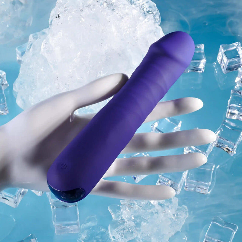 Purple thrusting vibrator with 10 speeds, held by hand, surrounded by ice cubes, showcasing phallic shape and texture.