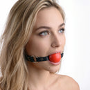 Strict Leather Red Silicone Ball Gag worn by a model, showcasing its bold design and adjustable leather strap.