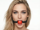 Strict Leather Red Silicone Ball Gag worn by a model, featuring a smooth silicone ball and leather strap for bondage play.