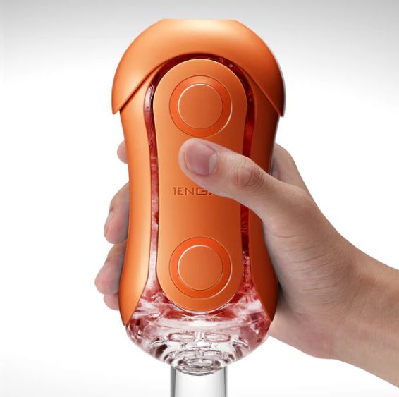 Tenga Flip Orb Sunset Orange Stroker held in a hand, showcasing its sleek design and ergonomic buttons for pleasure.