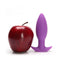 Neo Purple Anal Plug by Tantus beside a shiny red apple for size comparison, highlighting its beginner-friendly tapered design.