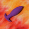 Neo Purple Anal Plug by Tantus on a vibrant background, showcasing its tapered design and beginner-friendly features.
