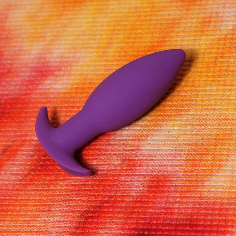 Neo Purple Anal Plug by Tantus on a vibrant background, showcasing its tapered design and beginner-friendly features.