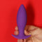 Hand holding the Neo Purple Anal Plug by Tantus, featuring a smoothly tapered design perfect for beginners.