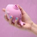 A hand holding Tracy's Dog Whalo Suction Clitoral Vibrator, showcasing its compact design and soft pink color.