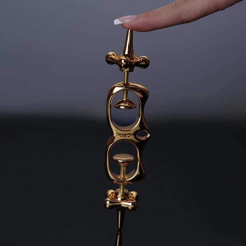 UPKO Thumb Metal Cuffs held by a hand, showcasing their sleek gold design and unique restraint mechanism.