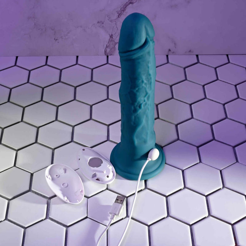 Realistic blue Tsunami vibrator with remote control and USB charger on white hexagon tile background.