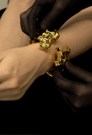 Person wearing UPKO Ripple Metal Handcuffs, showcasing their polished gold design and unique structured style.