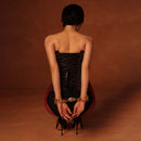 Model wearing UPKO Ripple Metal Handcuffs with elegant outfit, showcasing structured design and polished metal against warm background.