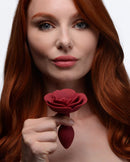 Master Series Booty Bloom Silicone Rose Anal Plug Small Red held by a woman with red hair, showcasing its unique floral design.