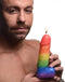 Man holding a colorful rainbow dick drip candle while it burns, showcasing a fun and playful ambiance.