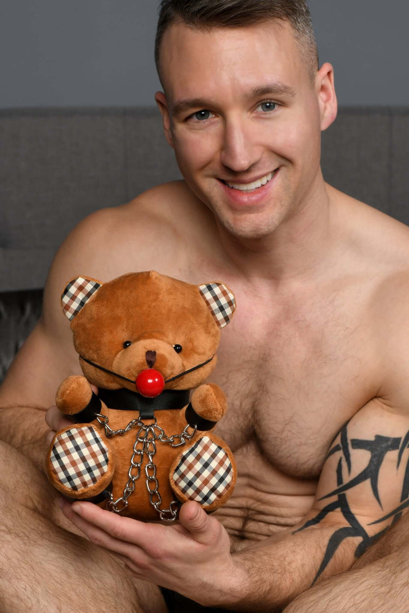 Smiling man holding Master Series Gagged Bondage Bear, featuring collar and cuffs, perfect for gifting or personal collection.