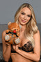 Model holding Master Series Gagged Bondage Bear, a plush toy with cuffs and a gag, showcasing playful BDSM elements.
