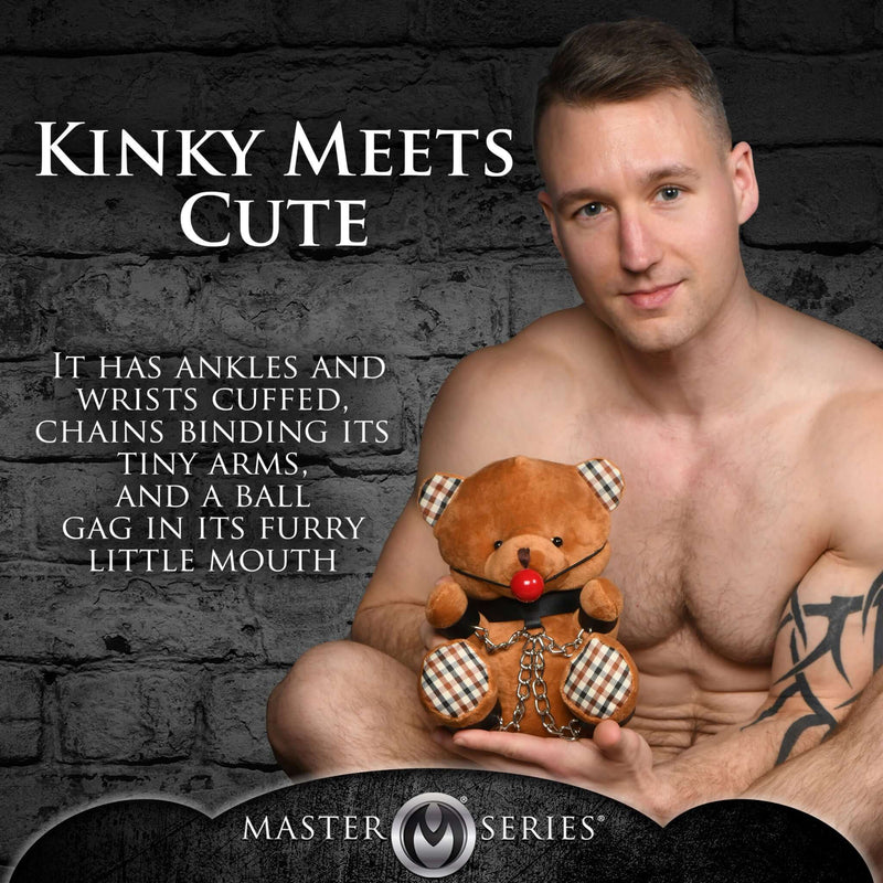 Master Series Gagged Bondage Bear with chains, cuffs, and ball gag, held by a man against a dark background.