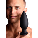 Master Series Colossus XXL Silicone Anal Suction Cup Plug held by a smiling man, showcasing its sleek design and size.