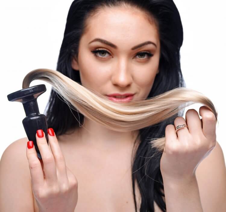 Woman holding a blonde ponytail butt plug, showcasing its silky texture and tapered design.