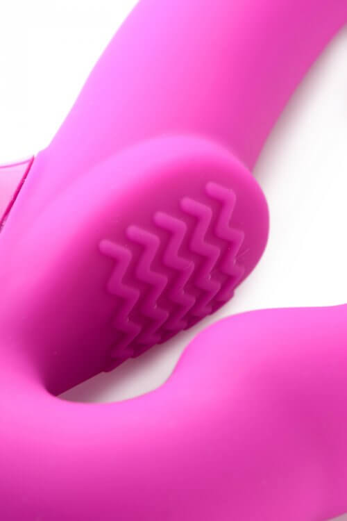 Close-up of the Strap U Evoke rechargeable pink silicone strapless strap-on with textured surface.