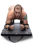 Image of a man on a black surface using the STRICT XL Padded Folding Bondage Board Black, showcasing restraint play.