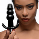 Frisky Ribbed Vibrating Butt Plug Black held by a model showcasing its playful design and smooth surface.