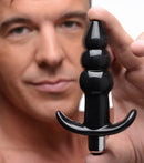 Frisky Ribbed Vibrating Butt Plug Black held by a man, featuring a three-bulb design and smooth surface for comfortable use.