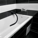 Hosed Swirled 18 Inch Thin Anal Snake Dildo Black on the edge of a bathtub against a sleek black and white tiled wall.
