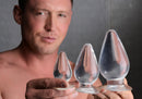Master Series Triple Cones 3 Piece Anal Plug Set Clear displayed by a model holding three graduated anal plugs.