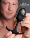 Heavy Hitters Premium Silicone Weighted Anal Plug Medium being held by a man, showcasing its sleek design and weighted feature.