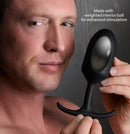 Heavy Hitters Premium Silicone Weighted Anal Plug XL Black held by a man, showcasing its sleek design and weighted interior ball.