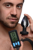 E-Stim Pro Silicone Vibrating Anal Plug with Remote Control held by a man with a digital controller showing intensity.