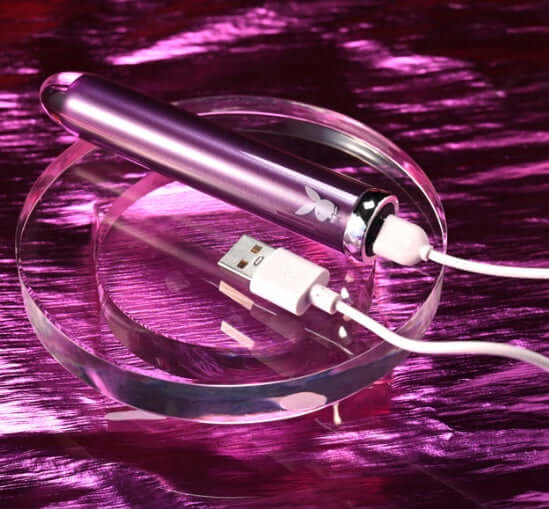 Playboy Amethyst Vibrator with glass tip and USB charger on pink background