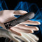 Evolved Back in Black Petite Vibrator with chrome tip and lined textures, held in a mannequin hand against a blue background.