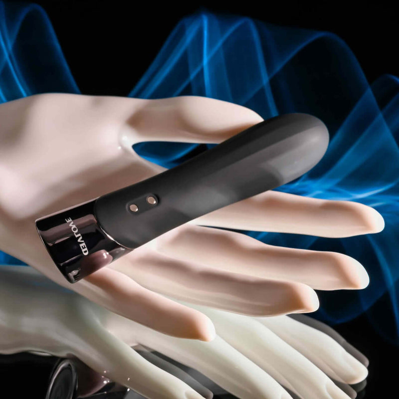Evolved Back in Black Petite Vibrator with chrome tip and lined textures, held in a mannequin hand against a blue background.