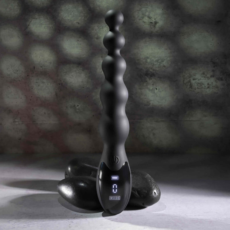 Flexible beaded vibrator with 9 speeds for intense backdoor play by ZERO TOLERANCE, displayed on smooth stones.