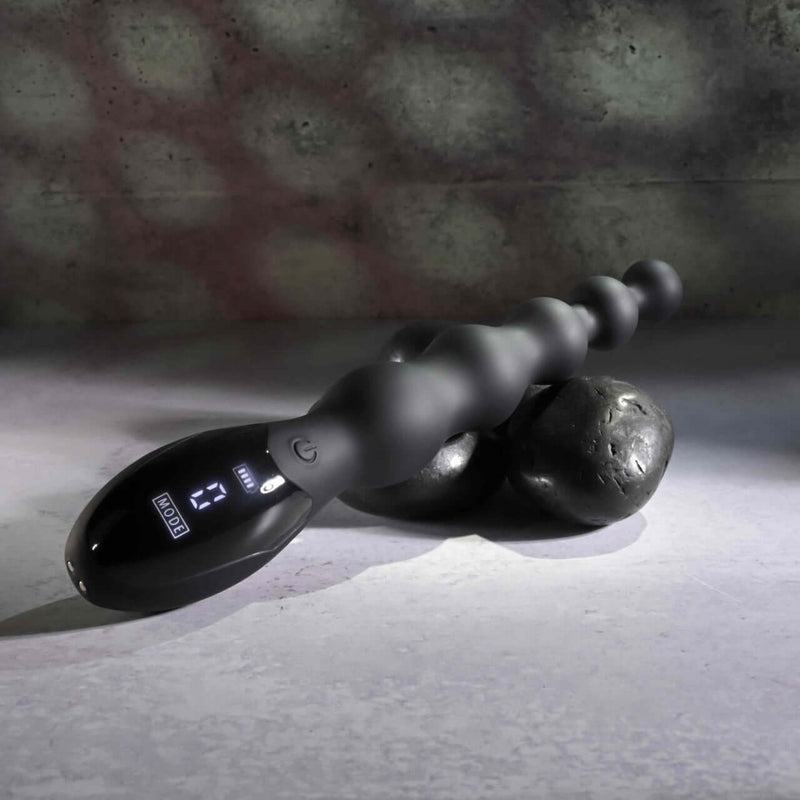Black flexible beaded vibrator with digital controls on stone background designed for intense backdoor play