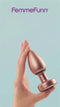 FemmeFunn Bougie Anal Plug Rose Gold held in hand against a light blue background.