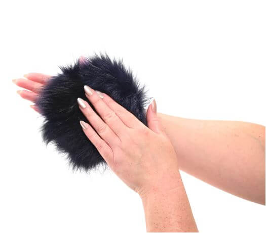 Person wearing blue faux fur sensory glove with hidden gold spikes for tactile play.