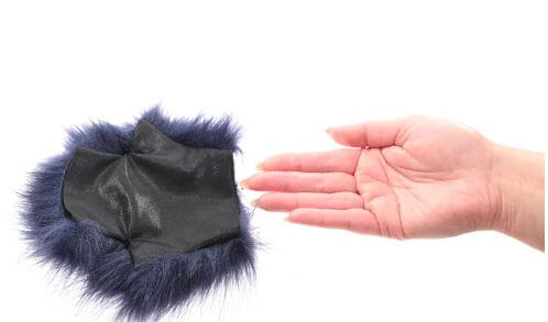 Blue faux fur glove with gold spikes next to an outstretched hand, showcasing texture and design for sensory exploration.