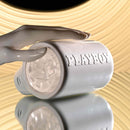 Hand holding PLAYBOY Spin Doctor dual entry spinning stroker with sleek black and pearl finish on a reflective surface.