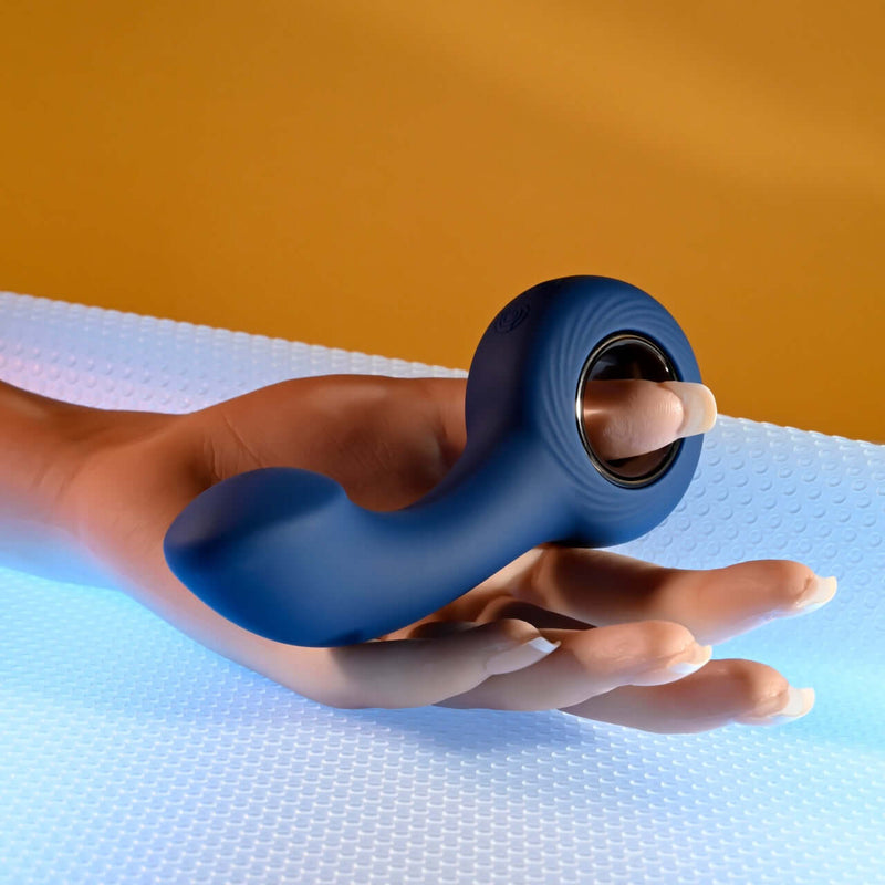 Vibrating P-Spot plug with ringed handle held in a hand, showcasing the flexible curved shaft and wide rounded tip.