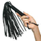 Hand holding Nocturnal™ Collection Flogger with black leather strands and sturdy handle for sensory play. Ideal for newcomers and enthusiasts.