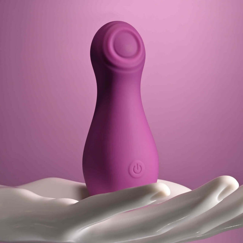 Playboy Jet Set Tapping Toy for Clitoral Stimulation in Purple on Hand Against Pink Background